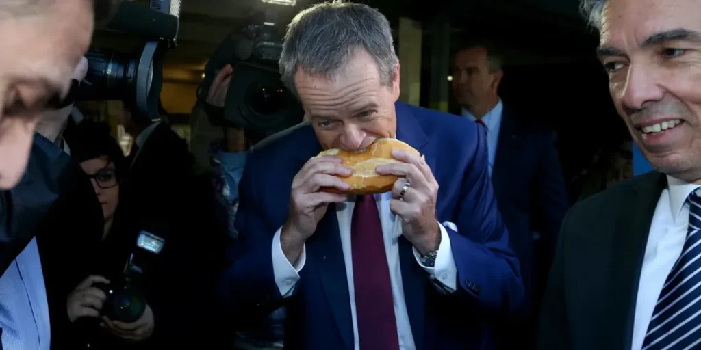 Bill Shorten biting into the middle of his democracy sausage